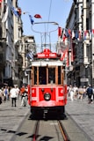 a red trolley car traveling down a street next to tall buildings