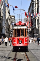 a red trolley car traveling down a street next to tall buildings