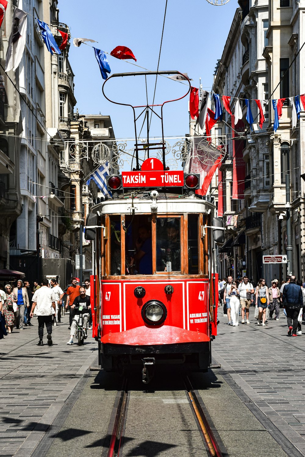 a red trolley car traveling down a street next to tall buildings