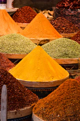 Stacks of colorful spices and dates displayed in a traditional market setting.
