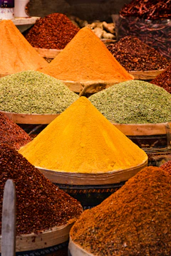 Stacks of colorful spices and dates displayed in a traditional market setting.
