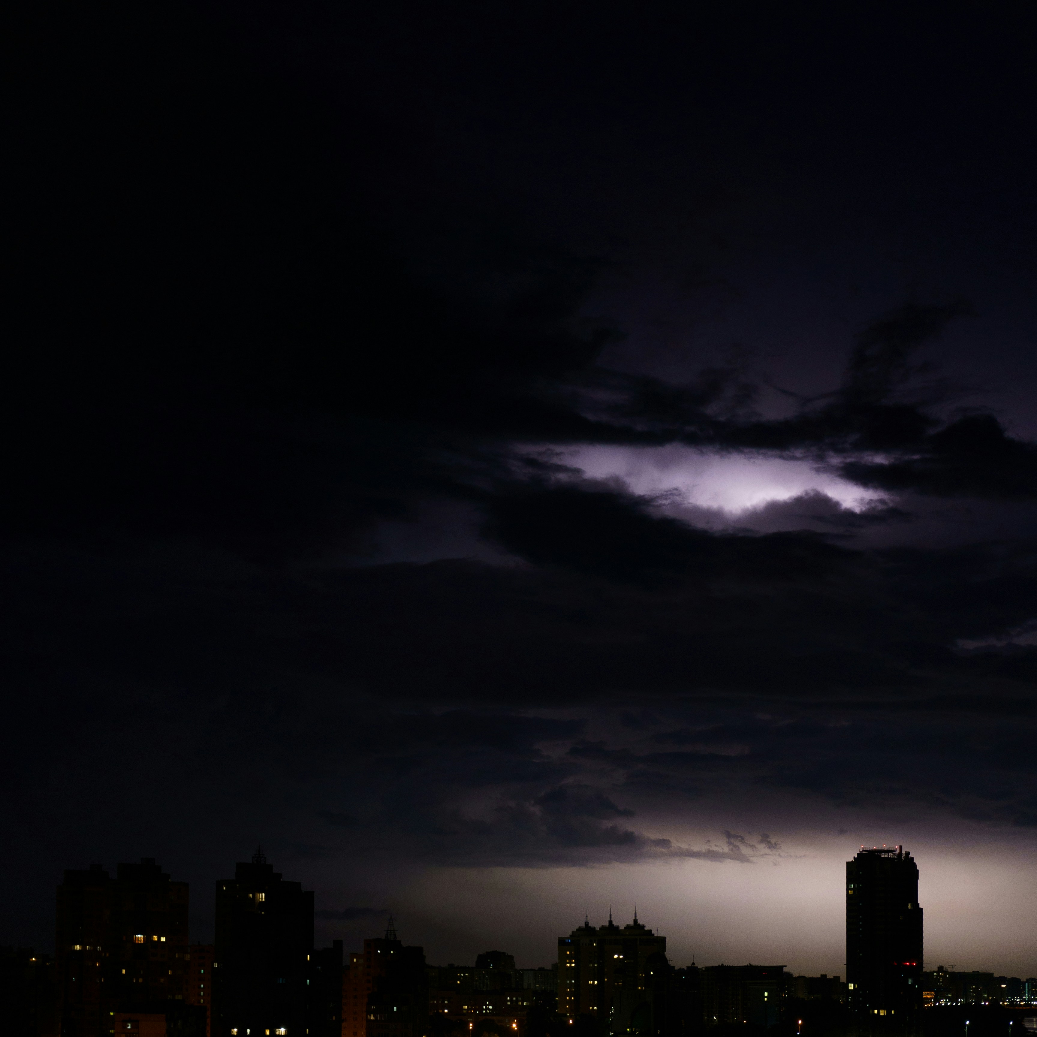 A lightning bolt is seen over a city at night photo – Free Nature Image ...