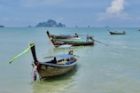Traditional long-tail boats lined up on a turquoise sea under a bright blue sky.