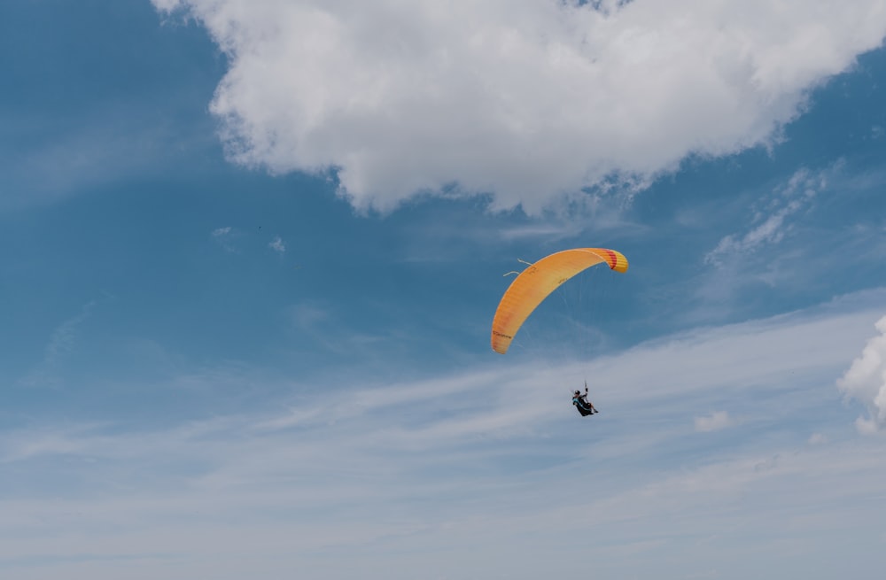 a person para sailing on the ocean under a cloudy blue sky