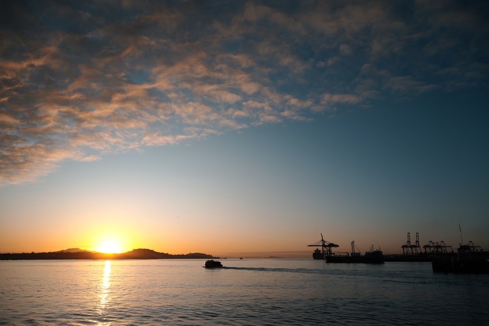 a boat traveling across a body of water at sunset