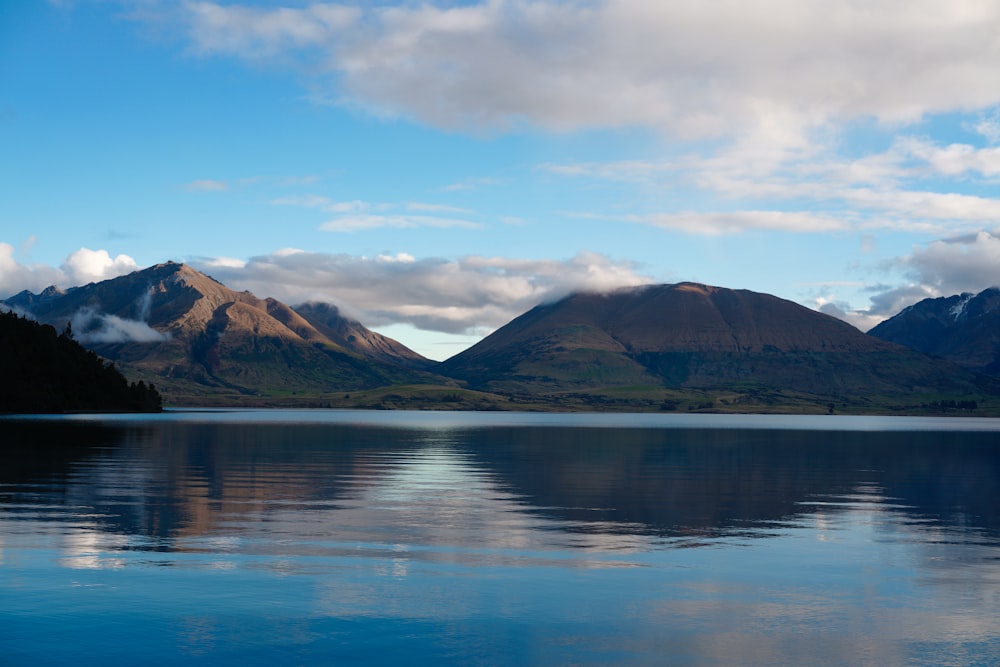 a lake with mountains in the background and clouds in the sky