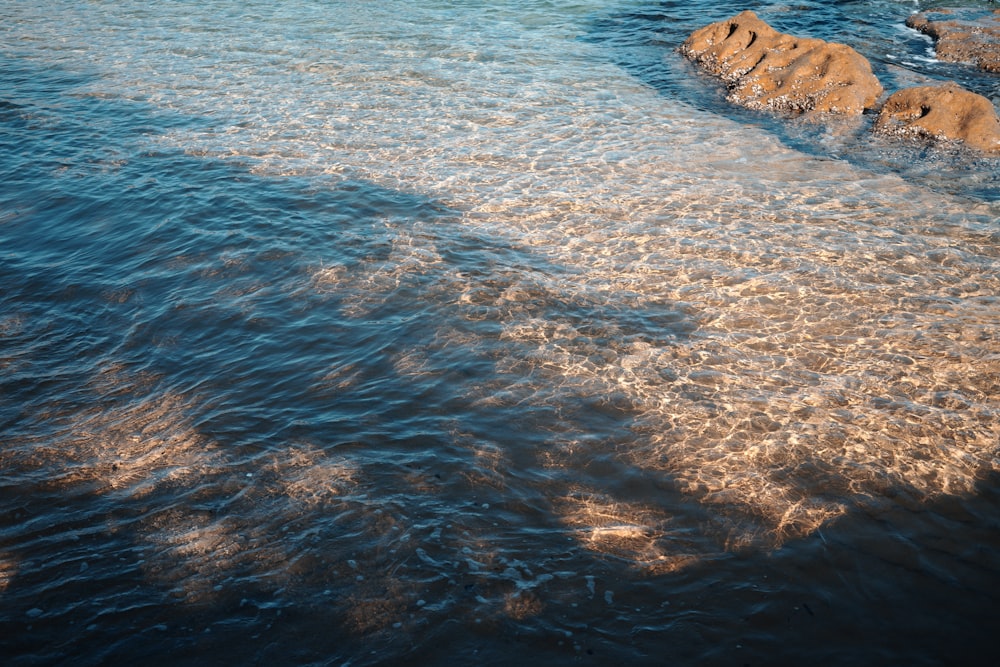 a body of water with rocks in the background