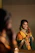 A smiling young Indian woman wearing delicate gold earrings and a beige silk scarf, showcasing elegant jewelry.