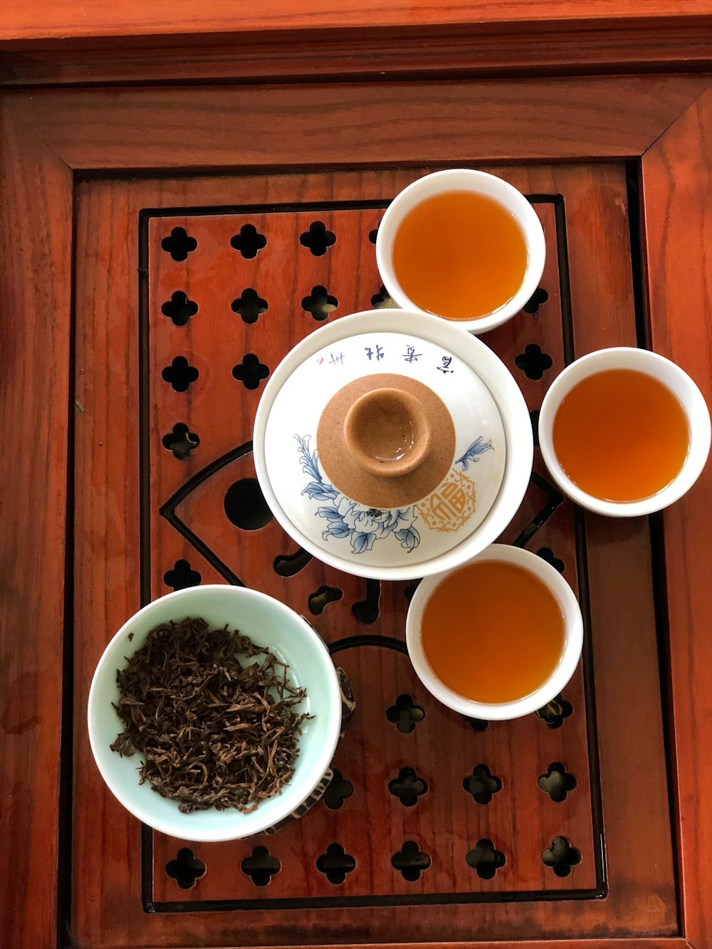 a wooden table topped with three bowls of tea