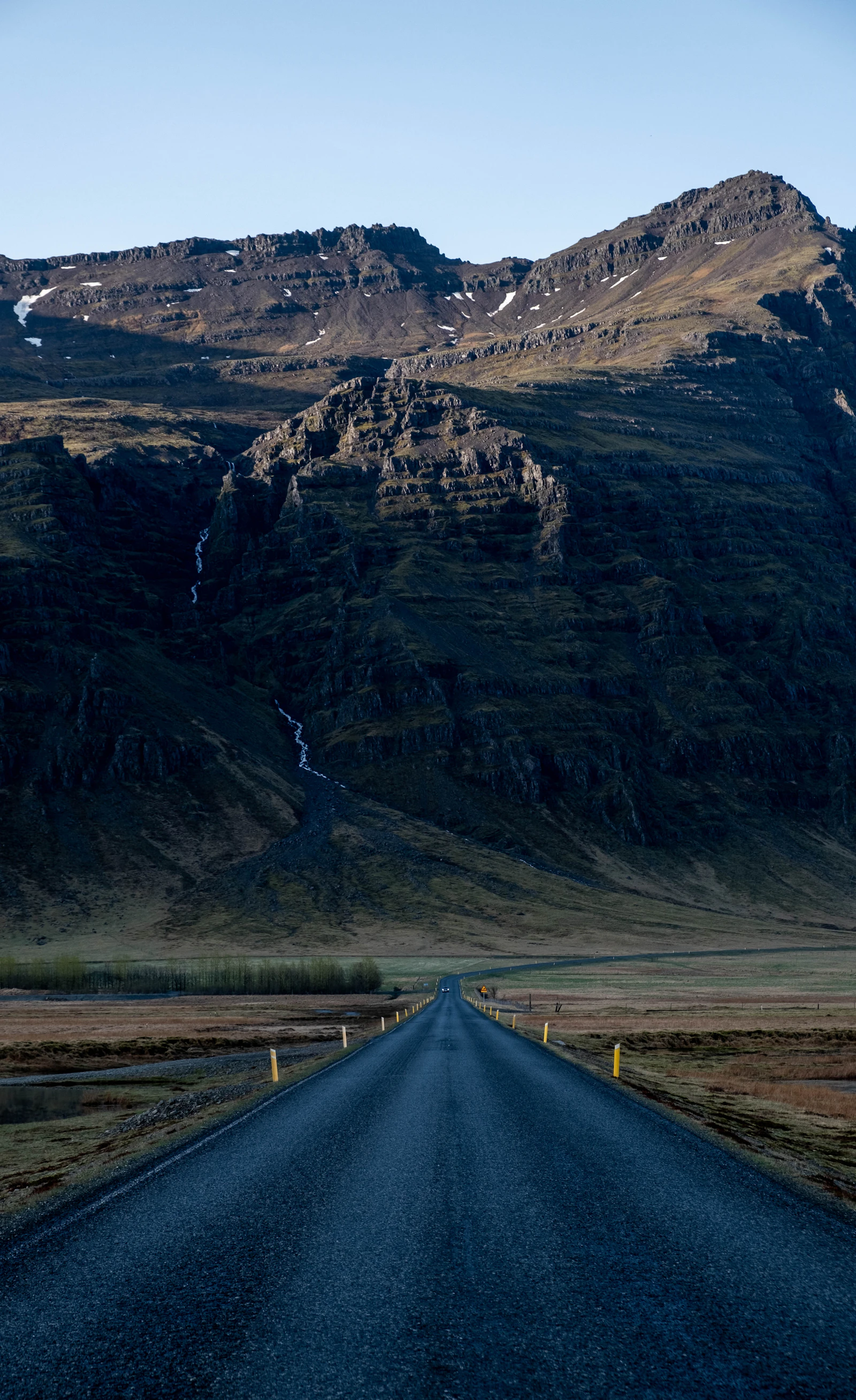 A long Icelandic road leading toward a mountain