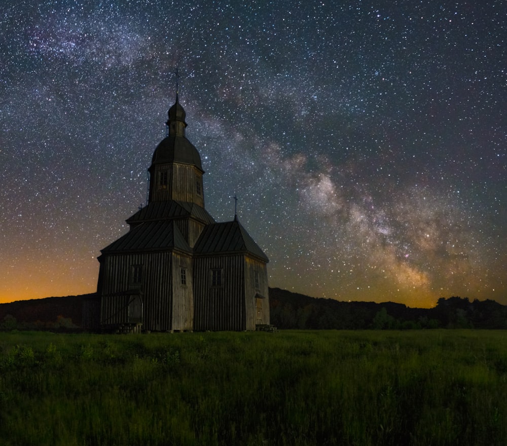 a church in the middle of a field under a night sky