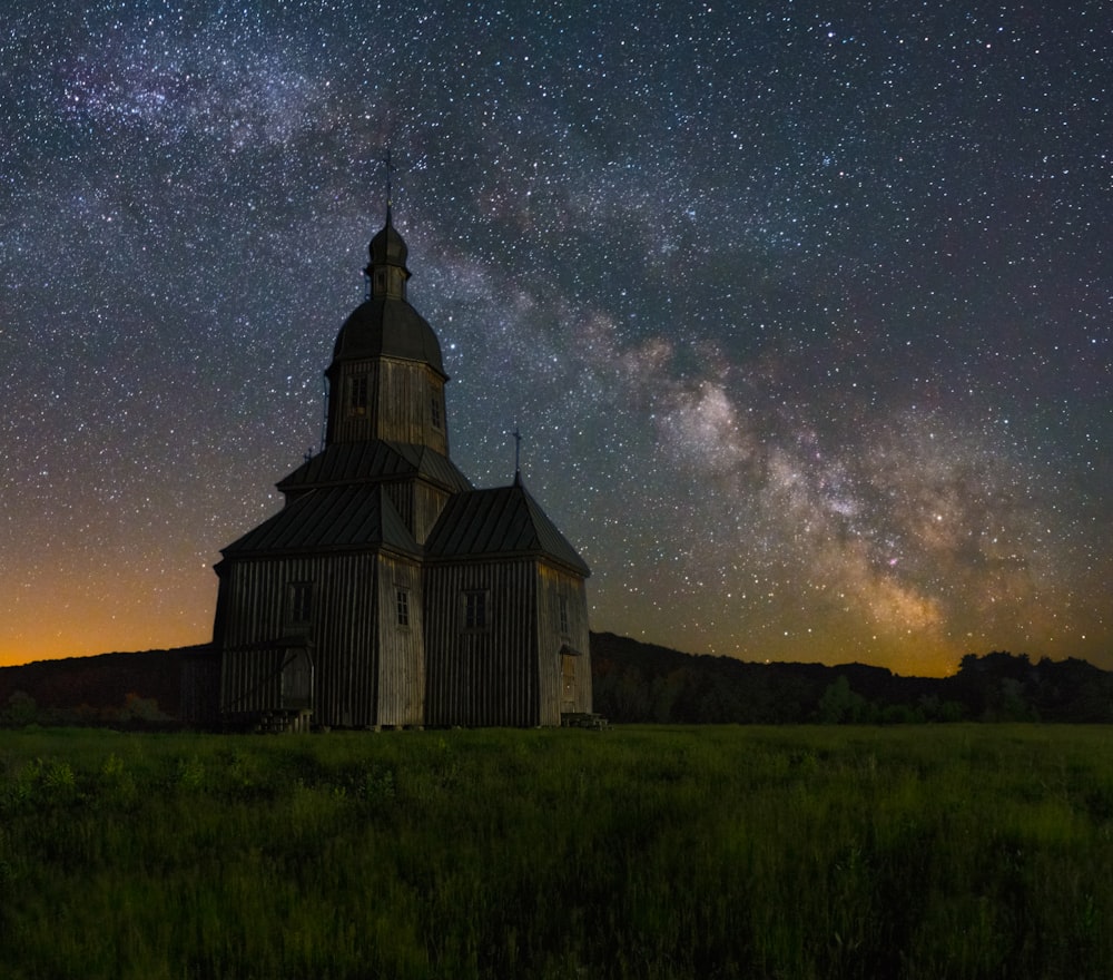 uma igreja no meio de um campo sob um céu noturno