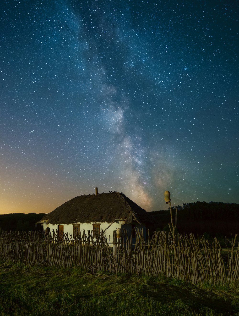 a house with a thatched roof under a night sky filled with stars