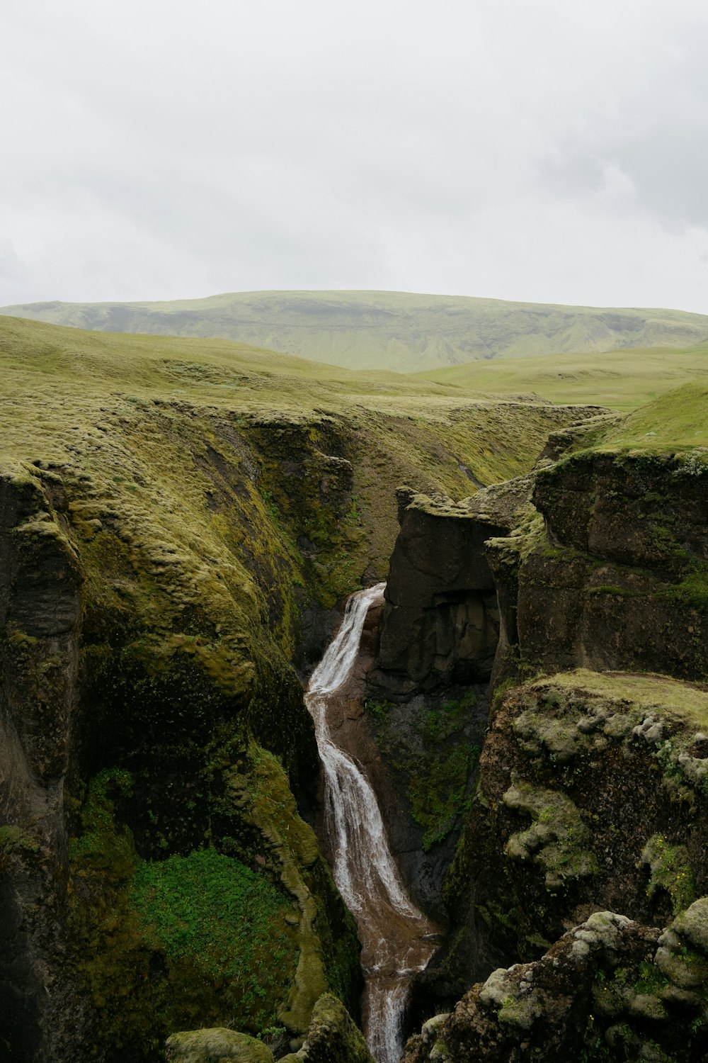 a waterfall in the middle of a green valley