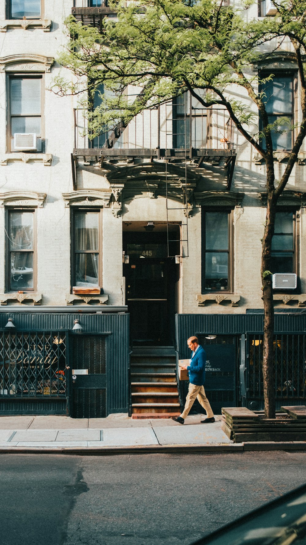 a man walking down a street past a tall building