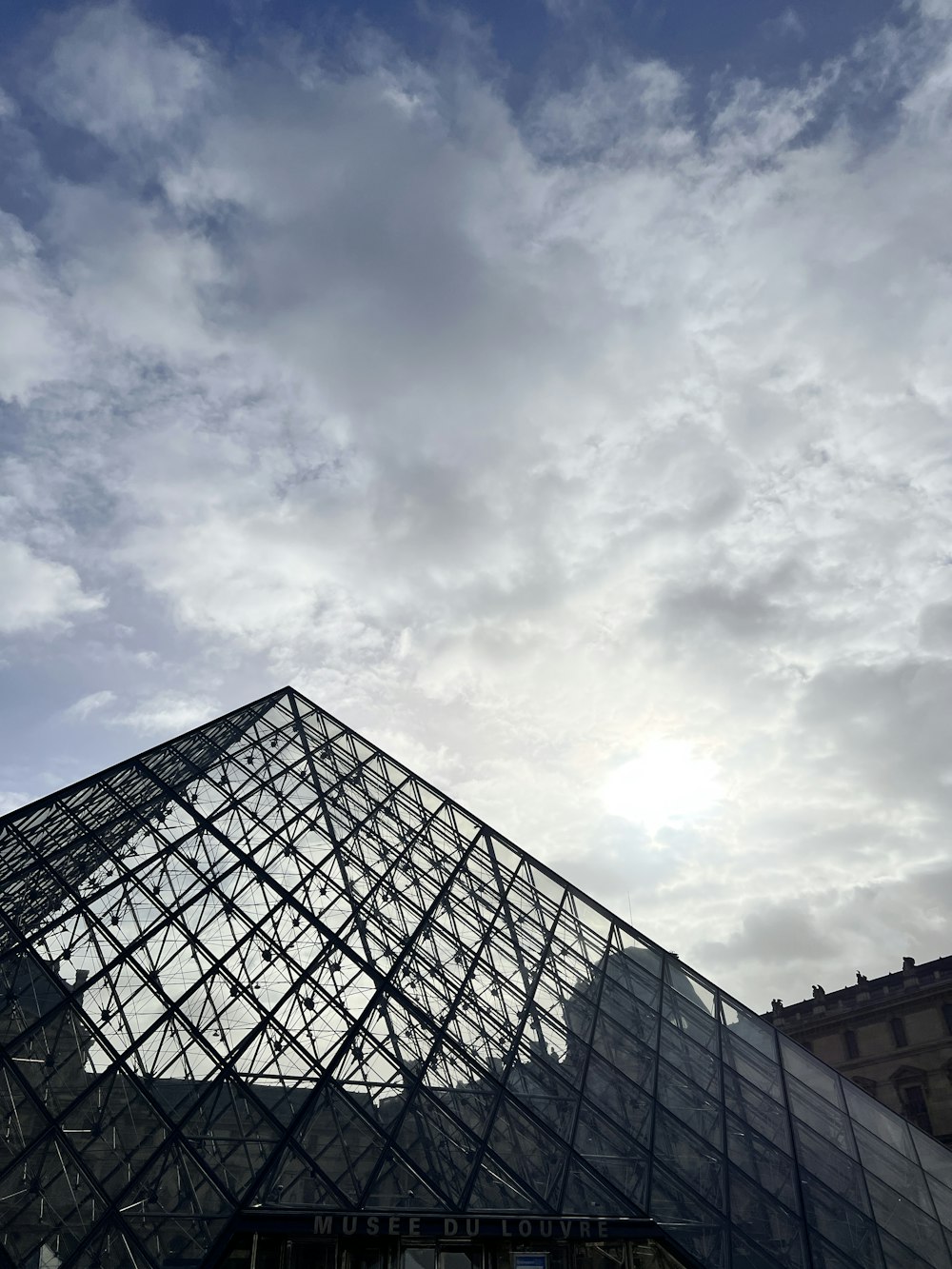 a very tall glass pyramid with a sky background