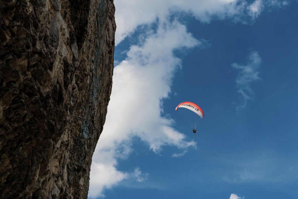 a parasailer is flying over a rocky cliff