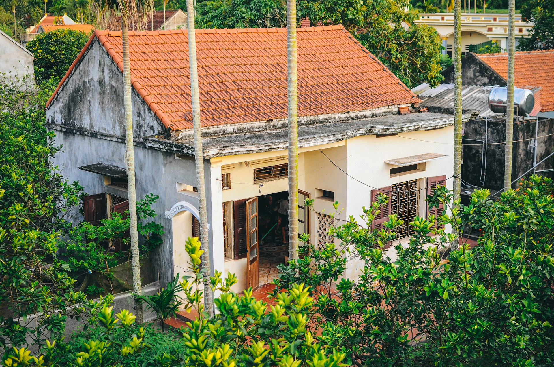 Cozy exterior shot of the finca's charming four-bedroom house with a rustic wooden kiosk and covered parking area.