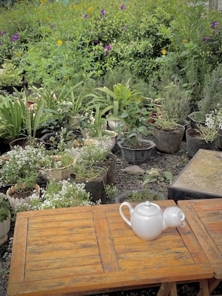 A rattan patio coffee table styled with a teapot and cups in a garden setting.