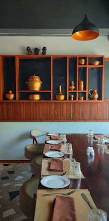 A rustic dining table set with a pure copper water jug and glasses.