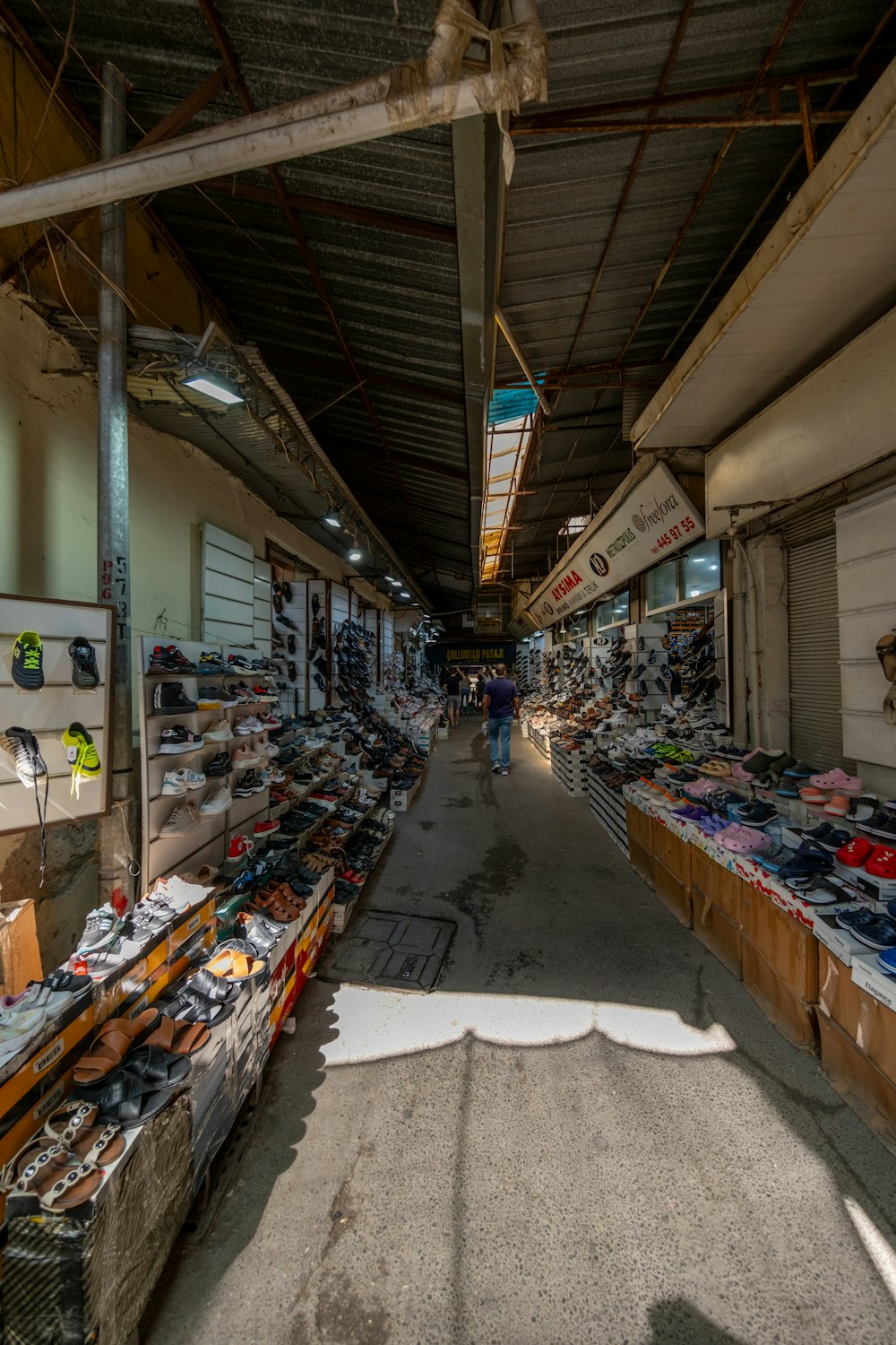 a man is walking through a market with lots of shoes