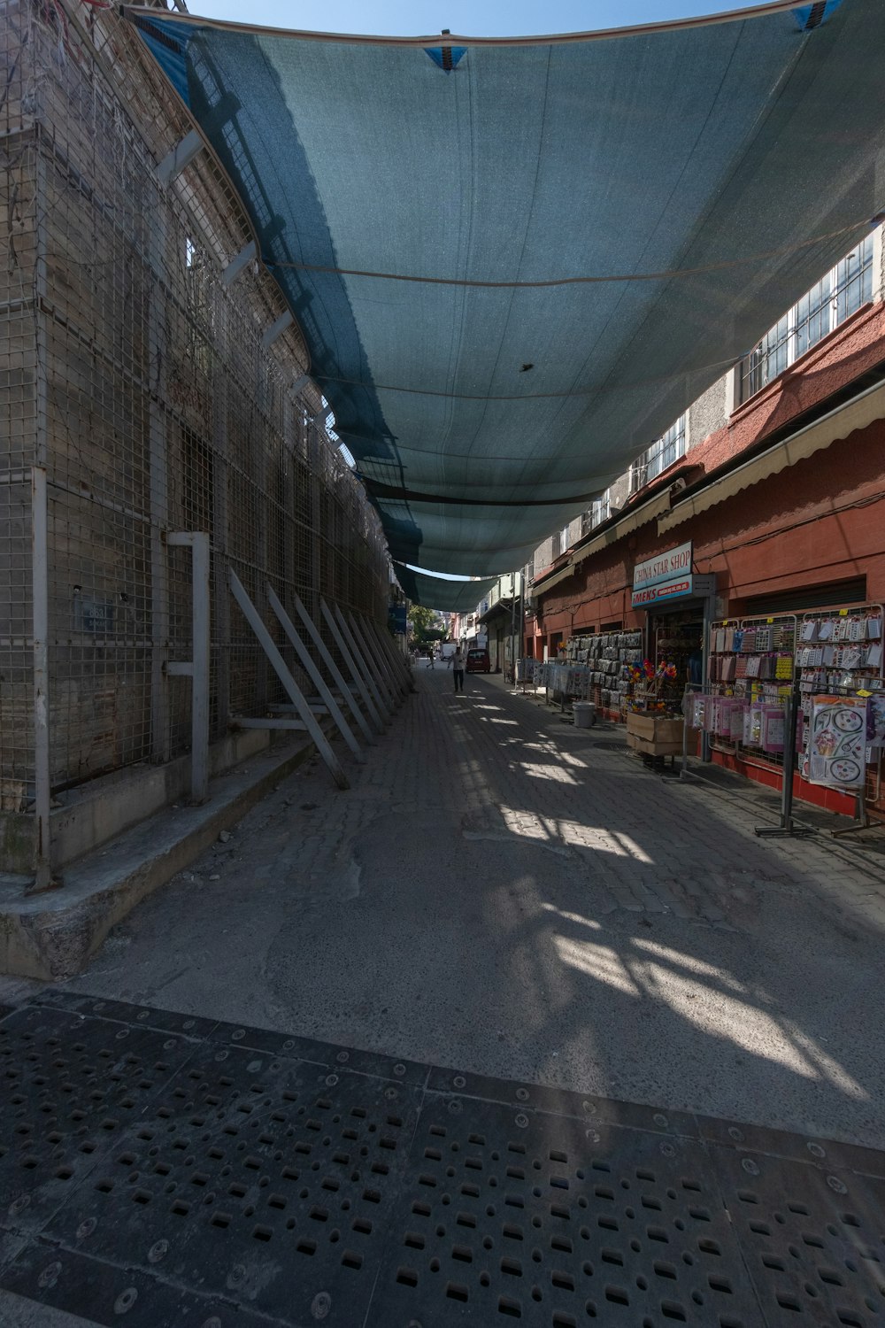 a street lined with lots of buildings under a blue tarp