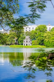 a lake surrounded by trees with a building in the background
