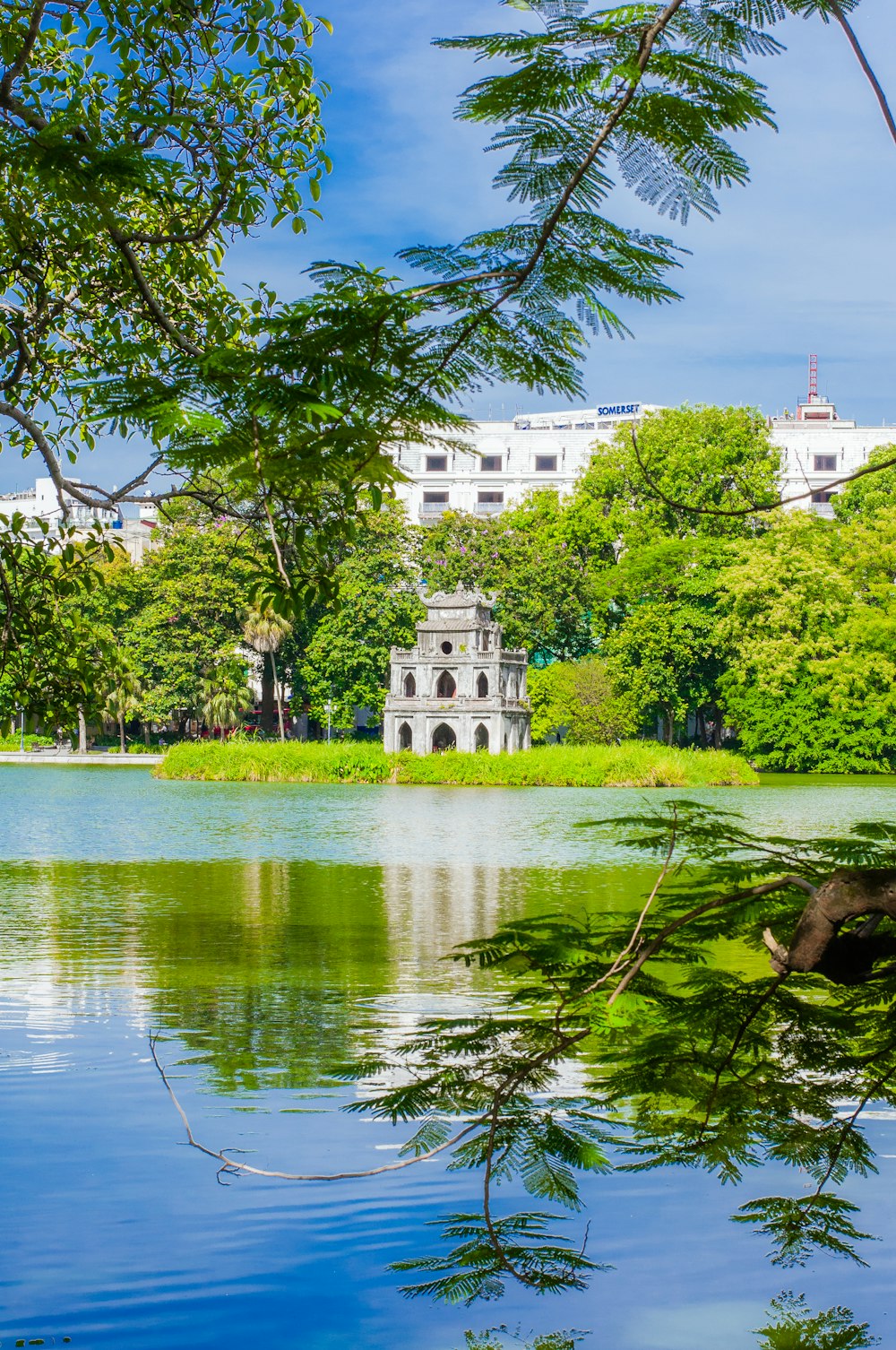 a lake surrounded by trees with a building in the background