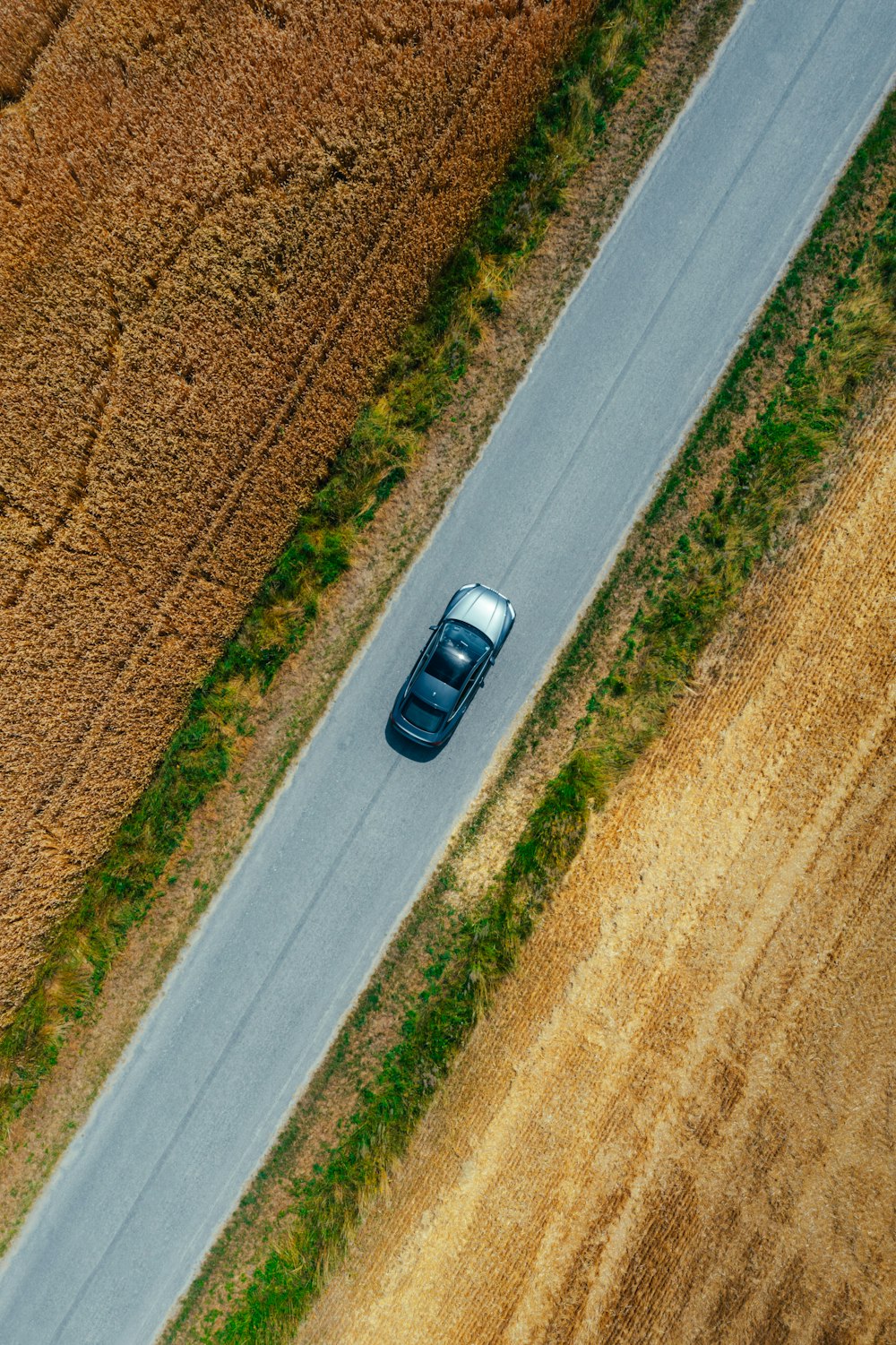 an aerial view of a car driving down a country road