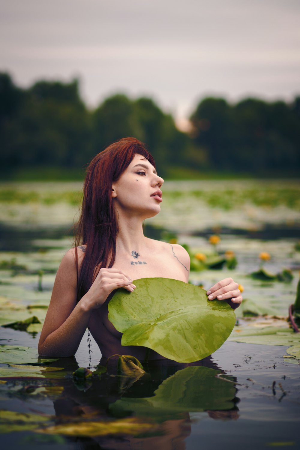 나뭇잎을 들고 있는 물가에 있는 여자