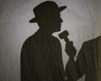 A collage of handwritten court papers, a microphone, and a shadowy figure with a baseball cap.
