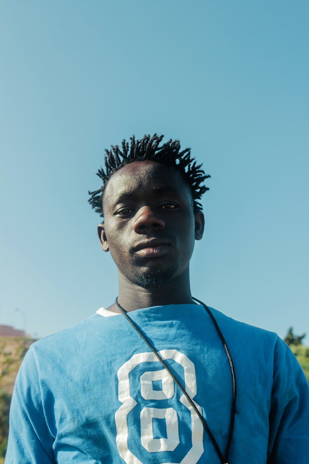 a man with dreadlocks standing in front of a blue sky