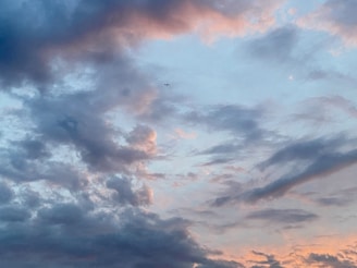 A serene sky with fluffy clouds and a distant airplane.