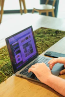 Close-up of hands designing a website layout on a tablet with forest green accents.