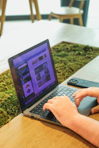 Close-up of hands designing a website layout on a tablet with forest green accents.