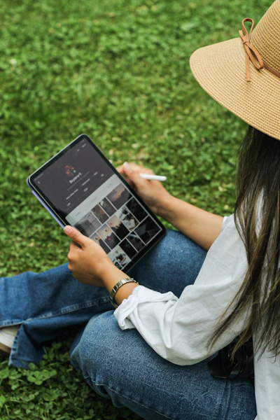 A woman sitting on the grass holding a tablet