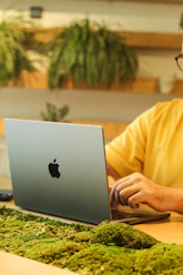 A friendly virtual assistant working on a laptop with blue and green accents in the background.