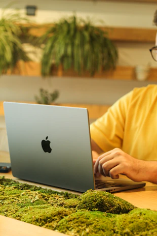 A friendly technician in a black and green uniform repairing a laptop in a cozy workshop.