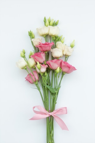 a bunch of pink and white flowers with a pink ribbon