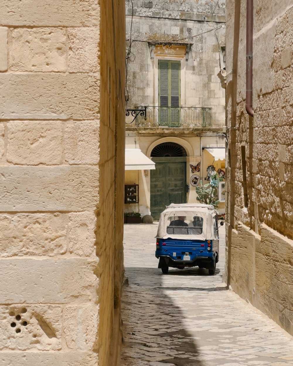 a small blue and white car driving down a street