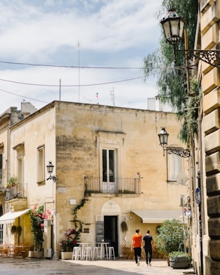 Nina smiling warmly beside a rustic café in a bustling foreign city