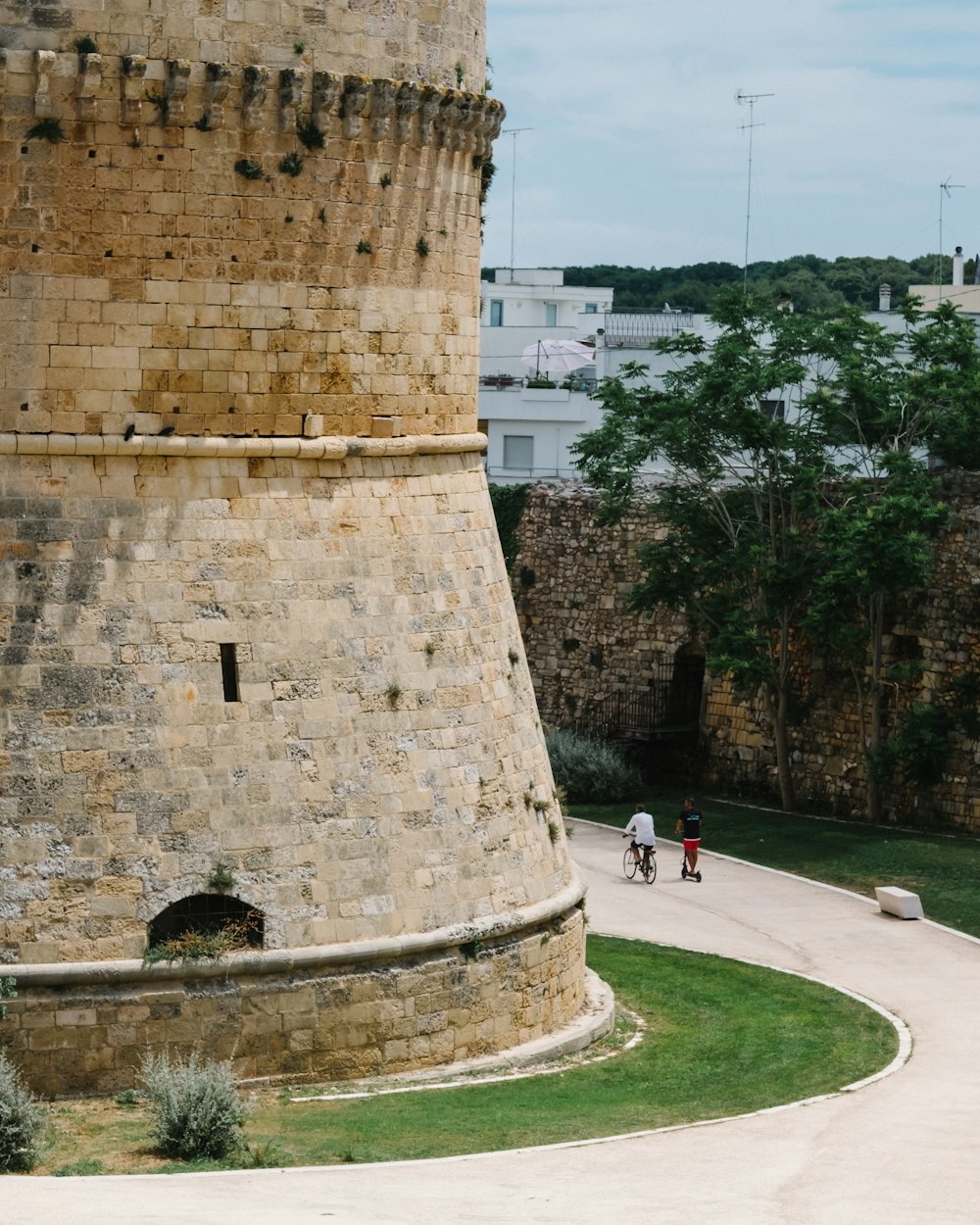 a man riding a bike past a tall brick tower