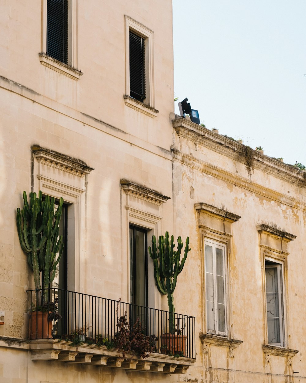 a tall building with a balcony with plants on it