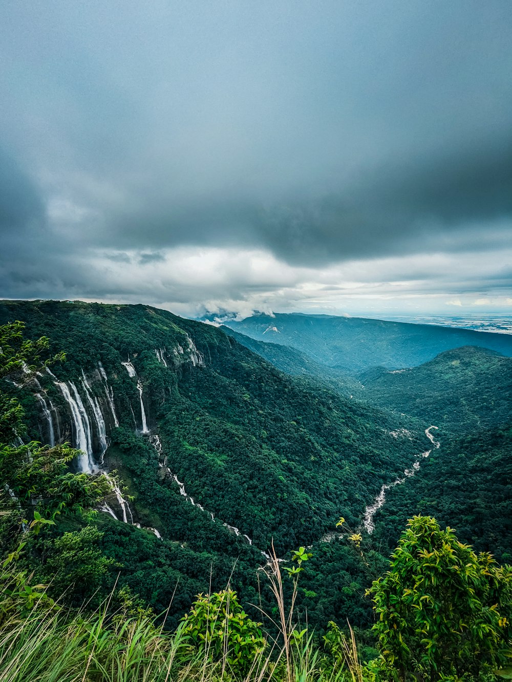 a lush green valley with a waterfall in the distance