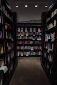 A well-organized aisle in a bookstore with shelves lined with a variety of books. The shelves are filled with colorful book covers, and there's a section labeled 'Mystery/Thriller'. Overhead lighting casts a warm glow on the book displays.