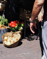 Close-up of a local farmer's hands holding fresh organic vegetables in a rustic market setting.