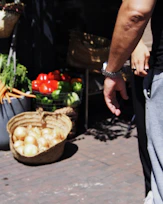 Close-up of hands carefully selecting fresh fruits and vegetables in a rustic Mexican market.