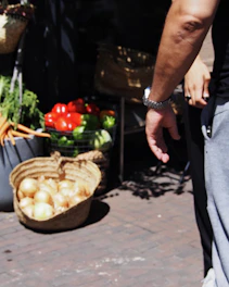Close-up of hands carefully selecting fresh fruits and vegetables in a rustic Mexican market.