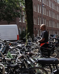 A delivery person unloading bicycles from a van in front of an office building.