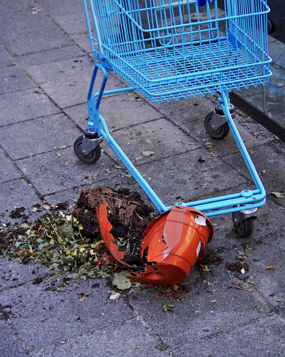 a blue shopping cart sitting next to a pile of dirt